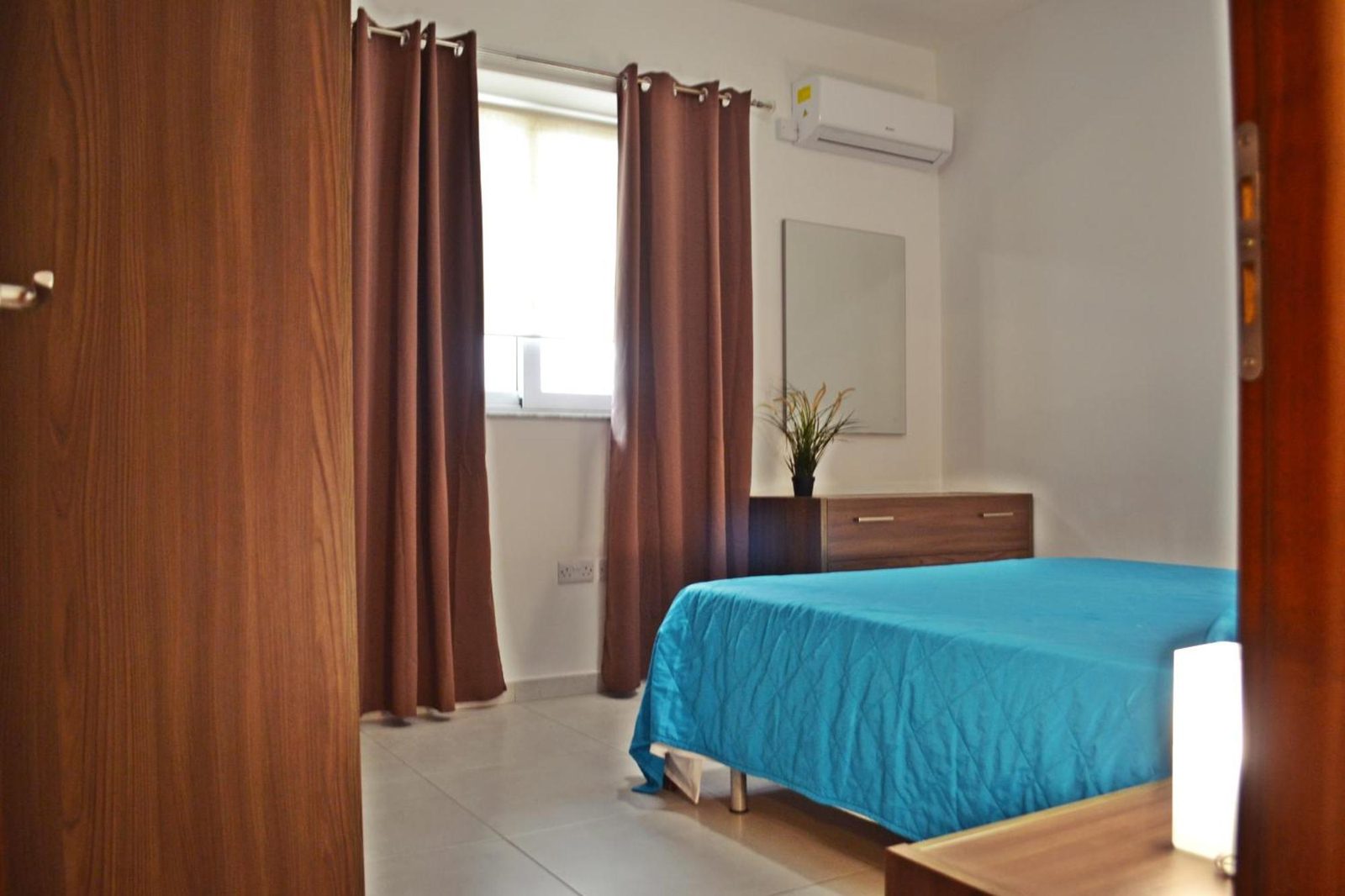 Double bedroom with brown curtains and air-conditioning